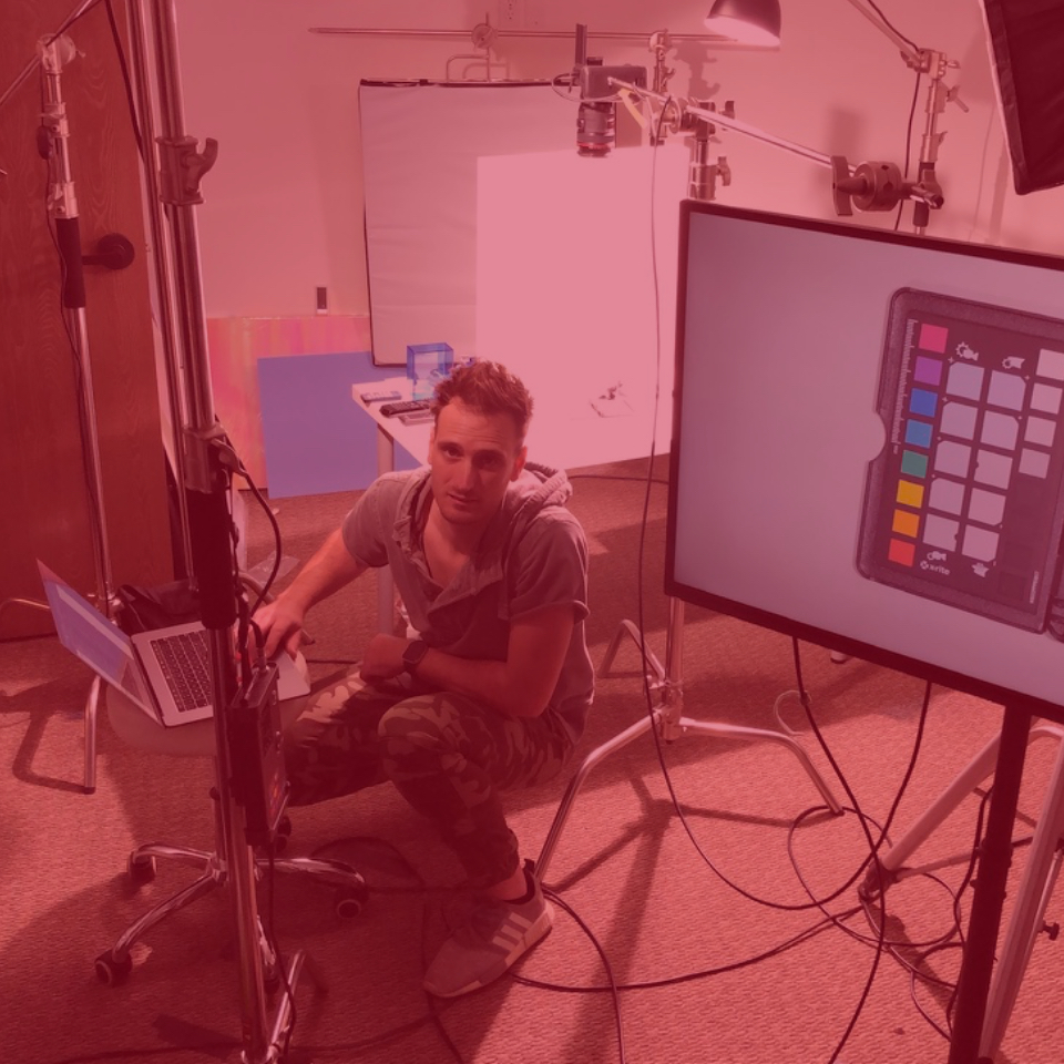 Steve Hood kneels at his laptop in a Studio next to equipment